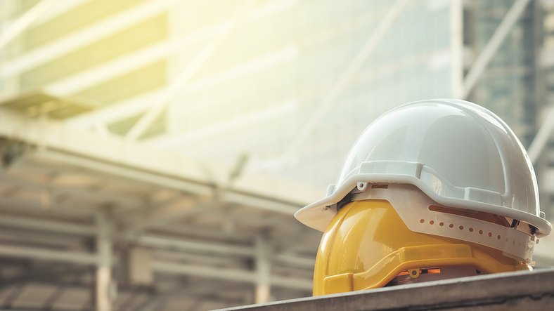 white, yellow hard safety helmet hat for safety project of workman as engineer or worker, on concrete floor on city